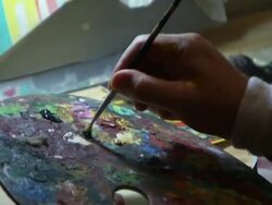 An artist mixes colors with a paintbrush on a palette. Stock Footage