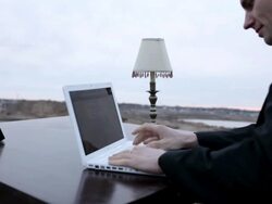 CU Young businessmand in black suit working on  his lap top while sitting at  table on top of  bluff in rural area  / Maple Grove, Minnesota, United States Stock Footage
