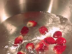 Mineral water pouring onto strawberries in steel bowl. Stock Footage