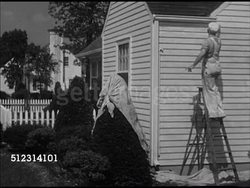 1947: HOUSE PAINTING: WS Male house painter on ladder painting exterior of home. CU Dipping broad brush into bucket of white paint. Decorator, tradesman, remodeling, coating, paint job Instructional Video