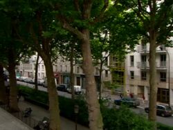 Long Shot pan-left tilt-down - Traffic travels on a street near a canal lock in Paris, France. / Paris, France Stock Footage