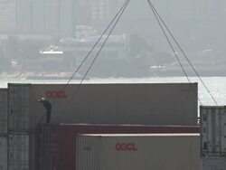 Dock worker stands on a shipping container as it is lowered onto dock by a crane, Hong Kong Stock Footage