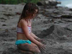 MS Little girl digs hole in sand then fills with sand while sitting on beach and singing song / Montezuma, Puntarenas, Costa Rica Stock Footage