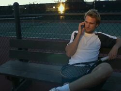 MS, Young man sitting on bench at tennis court, talking on mobile phone, Santa Barbara, California, USA Stock Footage