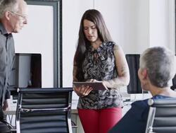 MS young businesswoman standing holding digital tablet in discussion with coworkers in office Stock Footage