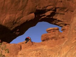 Photographer laying down inside massive sandstone arch -  zoom out Stock Footage