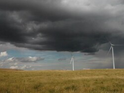 Wind farm on prairie with very dramatic clouds in sky and sun rolling across landscape. Stock Footage