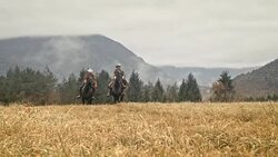 SLO MO Man and woman galloping on horses across meadow Stock Footage