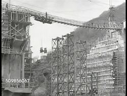 1946: FRANCE DAM CONSTRUCTION: WS Dam under construction. WS Large bucket of cement lowering. CU French worker releasing level on bucket, dumping cement. HA WS Dam construction, incomplete. Instructional Video