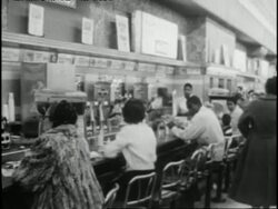 African Americans eat with caucasians at a Woolworth's lunch counter after the overturning of segregation laws. News Clip