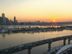 WS T/L View of Han River near National Assembly and traffic moving on bridge in Yeouido at Sunset / Seoul, Seoul, South Korea Stock Footage