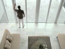 Elevated view of man entering living room, looking out of window, walking and using cellphone Stock Footage