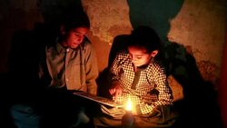 Two poor rural girls studying in lantern at home Stock Footage