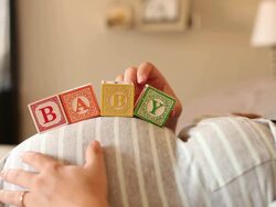 A pregnant women using blocks to spell the word BABY on her stomach. Stock Footage