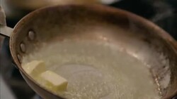 In restaurant kitchen, chef slides melting butter around steaming skillet in slow motion Stock Footage