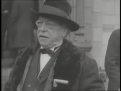 Union Leader Samuel Gompers stands next to another man and looks around. News Clip