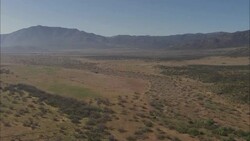 Dry, flat plains give way to a mountainous horizon. Stock Footage