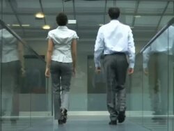 Man and woman walking down glass office corridor, UK Stock Footage
