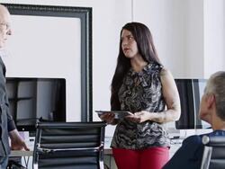 MS young businesswoman standing holding digital tablet in discussion with coworkers in office Stock Footage