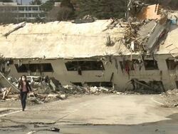 Destruction in Onagawa city, near Sendai Japan on 3rd April 2011; after tsunami following Tohuku earthquake of March 2011.  Woman running from ruined house Stock Footage