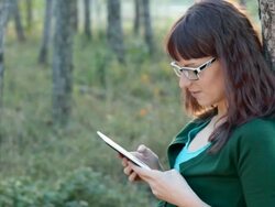 Young woman reading e-reader outdoors in park, smiling, resting. Stock Footage