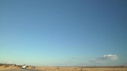 Best with sun rays down the highway - semi truck carries a backhoe on a trailer and drives down a rural highway and passes a farm tractor discing a field. Stock Footage