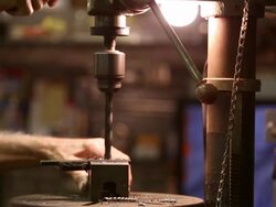 Workman in shop using a drill press Stock Footage