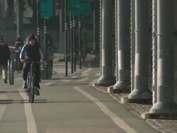 A telephoto shot of a man riding his bike under the FDR Highway on the lower east side of Manhattan Stock Footage