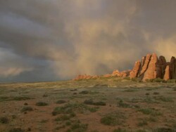 PAN Towering rock formations bathed in sunlight stand out in barren landscape at Arches National Park / Utah, United States Stock Footage