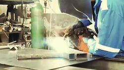 Welder in factory welding steel parts Stock Footage