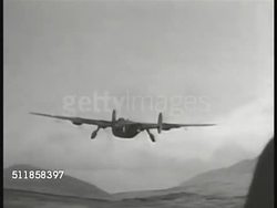 1942: PROTECTING the ALEUTIANS: B-24  'Liberator' heavy bomber in flight away from airfield toward mountains. AERIAL: Flying by Aleutian Mountains caldera volcanic crater.   WWII, Alaska, USA. Instructional Video