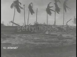 1942: PACIFIC THEATER: WS Smoky (low contrast) island destruction, broken palm trees, armored vehicle moving BG. WS PAN Bombed beach, war time destruction. World War II, WWII, Pacific Ocean Area, Campaign, Front. Instructional Video