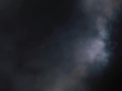 Wide shot full moon partially obscured by heavy clouds in night sky Stock Footage