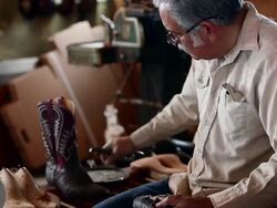 MS TD boot maker using tool to stretch leather and place tacks in sole of cowboy boot Stock Footage
