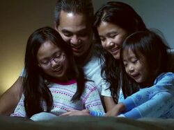 Family in bed together reading Stock Footage