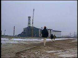 1996 wide shot Chernobyl nuclear plant / men walking past in foreground / 10 year anniversary of disaster Stock Footage