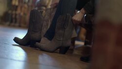 Young woman tries on cowboy boots with friend and dances around Western store Stock Footage