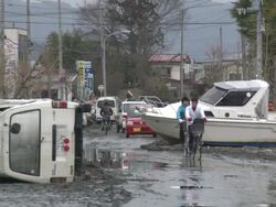 Destruction caused by tsunami after magnitude 9 Tohoku earthquake, north east Japan, March 2011. People moves past wrecked car and boat after tsunami in Ishinomaki City,  Miyagi Prefecture Stock Footage