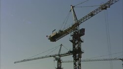 Construction cranes operate high above a city. Stock Footage