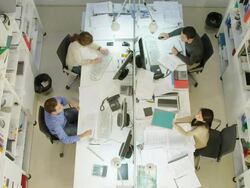 HA WS two men and two women working on  desk in modern office, one woman handing folder across table to man Stock Footage