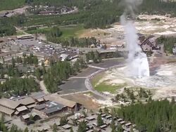 WS ZI AERIAL View of tourist watching hot water fountain at Emerald Pool with car parking area and houses / Wyoming, United States Stock Footage
