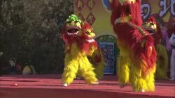 A martial artist performs while entertainers in dragon costumes dance on a raised stage. Stock Footage