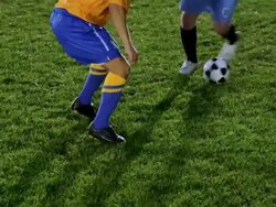 MS SLO MO PAN professional soccer player dribbling ball past opposing defender on field at night Stock Footage
