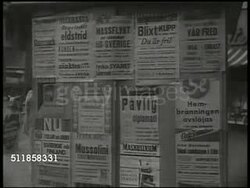 1941: URBAN SWEDEN: People standing, reading posting on side of news stand, others walking FG. WWII war related postings on side of news stand. VS Anti-Nazi Swedish editor Dr. Torgny Karl Segerstedt (1876-1945) working at desk. Instructional Video