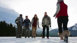 Friends jumping for joy hugging in snowy field Stock Footage