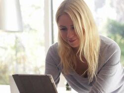Young female looking at ipad and drinking tea in kitchen Stock Footage