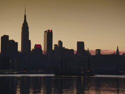 Commercial crane boat floats down the hudson river in the early morning sun in front of the empire state building and the manhattan skyline Stock Footage