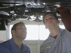 MS Mechanic standing together under car, points something out to coworker / Seattle, Washington, United States  Stock Footage