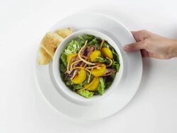 CU Woman hand entering setting down round white bowl of lettuce with mandarin oranges on top / Omaha, Nebraska, United States Stock Footage