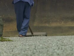  MS Sandal wearing feet slowly stepping backwards methodically guiding rake in Ryoan-ji AUDIO / Kyoto, Kansai, Japan Stock Footage